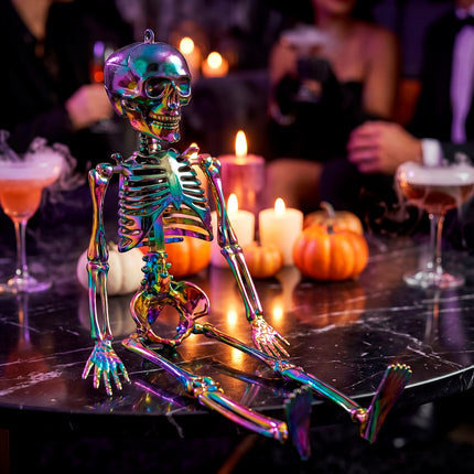 Metallic regenboog skelet op tafel tussen kaarsen en pompoenen op een Halloweenfeest