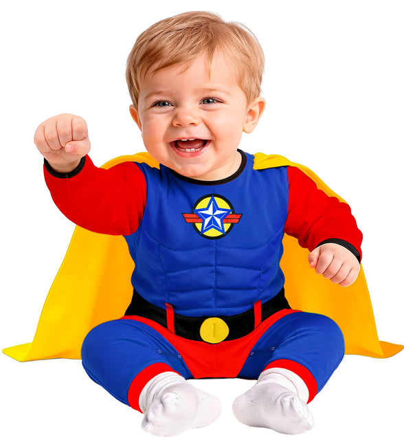 Blauw superheld babypakje met sterembleem op de borst en gele cape, zittende baby