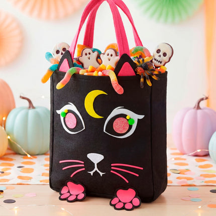 Snoeptas kat gevuld met snoep tussen pompoenen als Halloween-decor