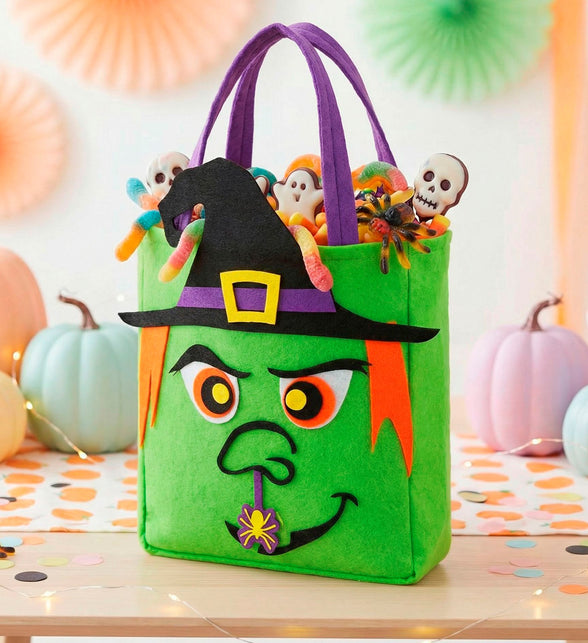 Trick-or-treat tas heksen met snoep tussen pompoenen op een Halloweentafel