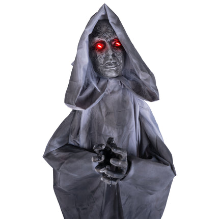 Biddend vrouwenbeeld animatronic van dichtbij met rode ledogen en grijze haarslierten, voor Halloween