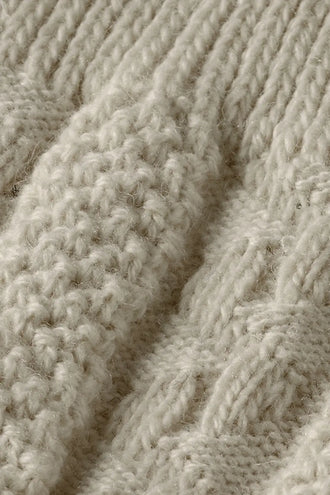 Close-up van de geribde boord en het reliëfbreisel van de Tiroler kniekousen off white