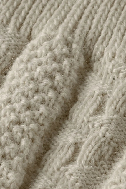 Close-up van de geribde boord en het reliëfbreisel van de Tiroler kniekousen off white