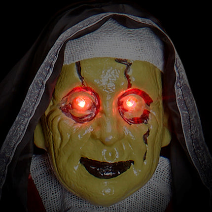 Detail van het groengele nonnenmasker met gescheurde huid en rood oplichtende ogen