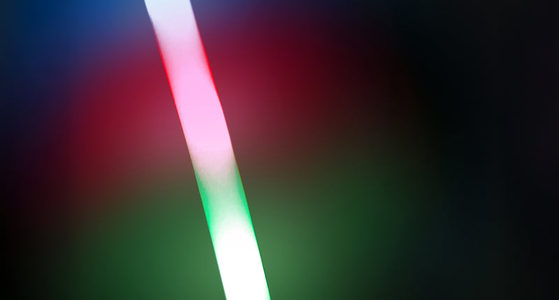 Foam stick led 48 cm in de hand, oplichtend in blauw, rood en groen op een donker feest