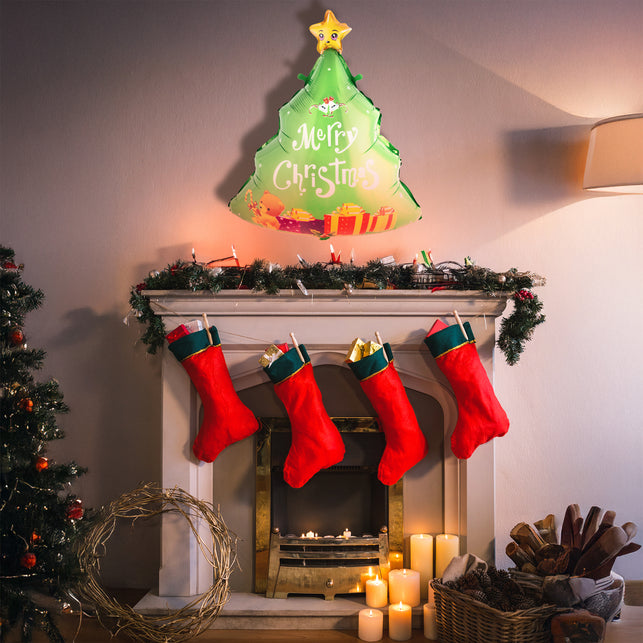 Folie ballon kerstboom Merry Christmas hangend boven een schoorsteenmantel als kerstdecoratie tijdens Kerst