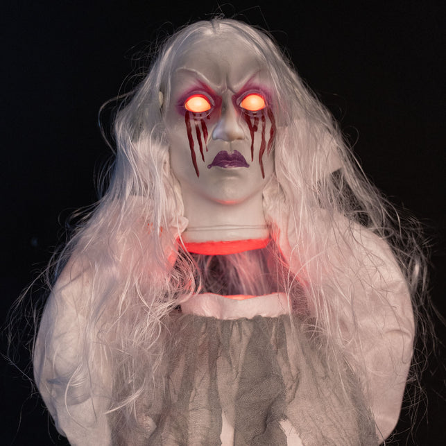 Geest animatronic in close-up met rood oplichtende ogen en bloedstrepen over de wangen