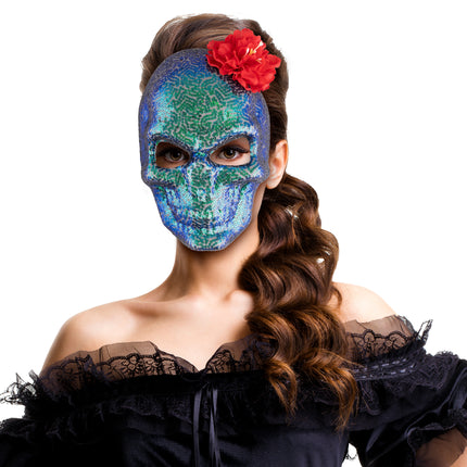 Glitter schedelmasker gedragen door vrouw met zwarte kanten jurk en rode bloem in het haar
