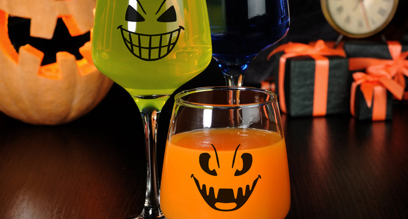 Halloween glasstickers met zwarte griezelgezichten op een wijnglas en bierglas voor Halloween