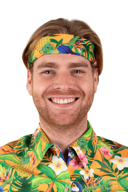 Hawaii zakdoek oranje met toekans en ananassen, als hoofdband geknoopt op een hawaiifeest