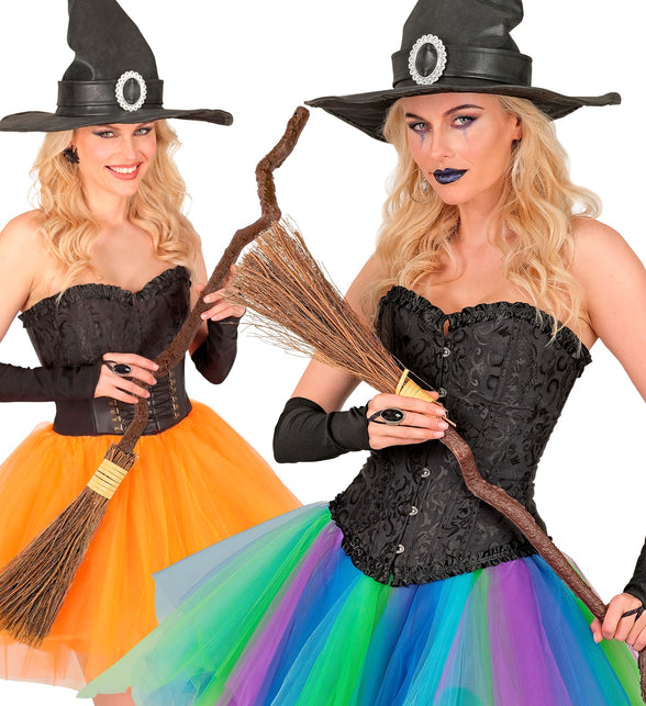 Heksenbezem krom in de hand bij zwart heksenkostuum met puntige hoed voor Halloween