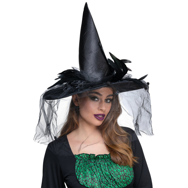 Luxe heksen hoed in zwart met veren, satijnen roos en tule sluier, gedragen door een dame op Halloween