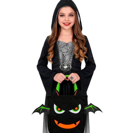 Meisje draagt de zwarte vleermuis snoeptas met twee handen tijdens Halloween