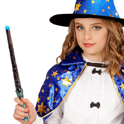 Meisje houdt het oplichtende toverstokje vast bij een blauwe punthoed met sterren