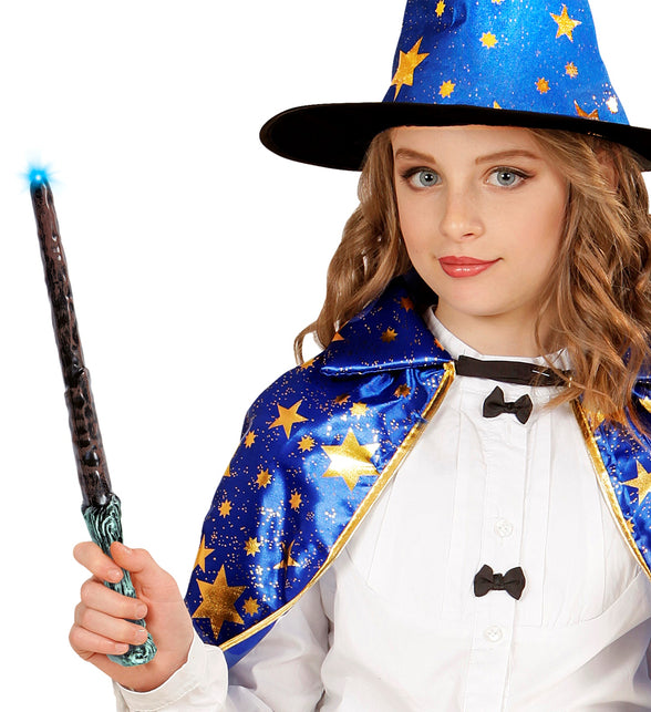 Meisje houdt het oplichtende toverstokje vast bij een blauwe punthoed met sterren