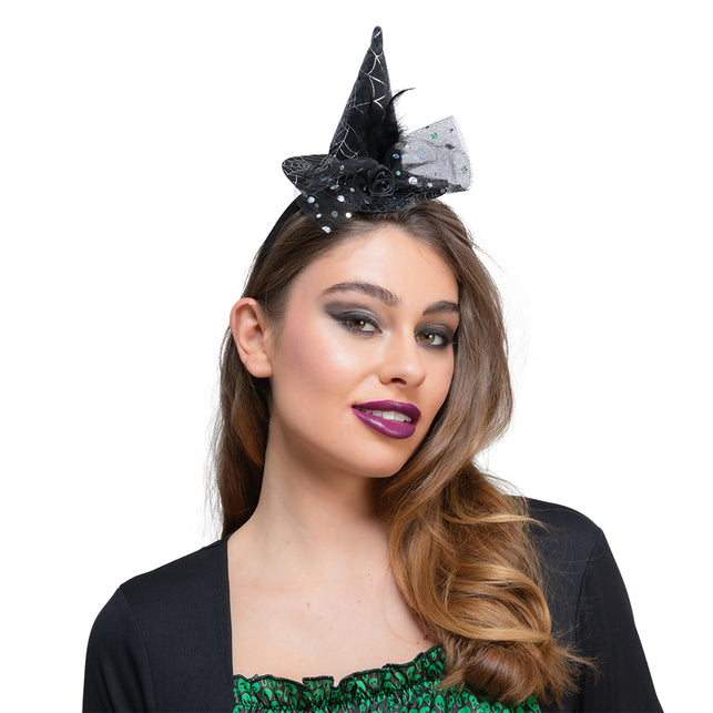 Mini heksenhoed op hoofdband in zwart met spinnenwebprint en tule strik, gedragen voor Halloween