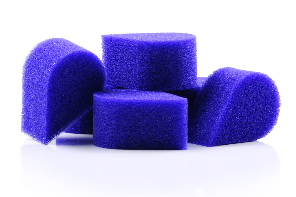 Paarse bloembladsponsjes met grofporige structuur, detail van vier losse schminksponsjes