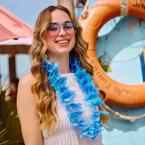 Partybril Shade met roze verloopglazen op een beach party, gecombineerd met een blauwe bloemenkrans