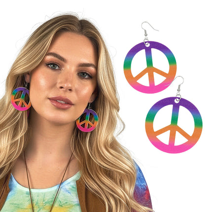 Peace oorbellen in regenboogkleuren gedragen door een vrouw met lang blond haar, outfit voor een hippiefeest