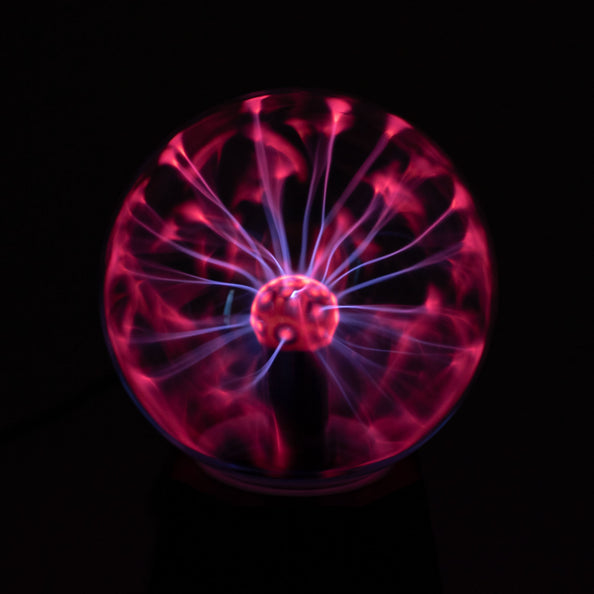 Plasmalamp met roze en violette lichtbogen in de glazen bol, oplichtend in het donker