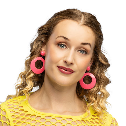 Retro oorbellen neonroze bij losse krullen, de ringhangers vallen langs de kaak