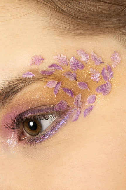 Roze en paarse blaadjes in wax rond het oog gelegd over glinsterende oogschaduw, feeënlook