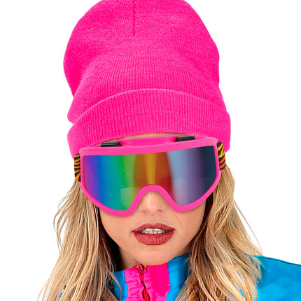 Ski-bril 80's roze regenboog gedragen onder een felroze muts op een aprèsski-look