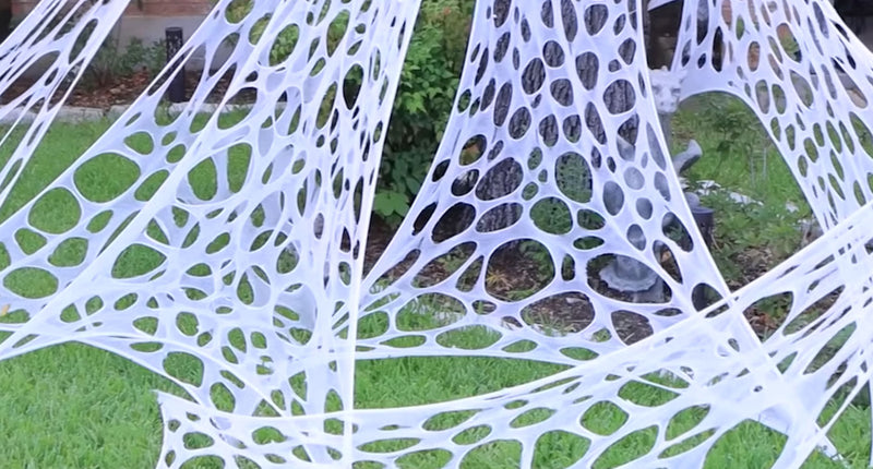 Spinnenweb met gaten wit opgehangen in de tuin met grote ronde gaten, Halloween decoratie