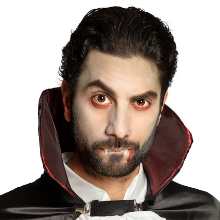 Vampierlook met bleek geschminkt gezicht, donkere ogen, vampiertanden en bloedspoor voor Halloween