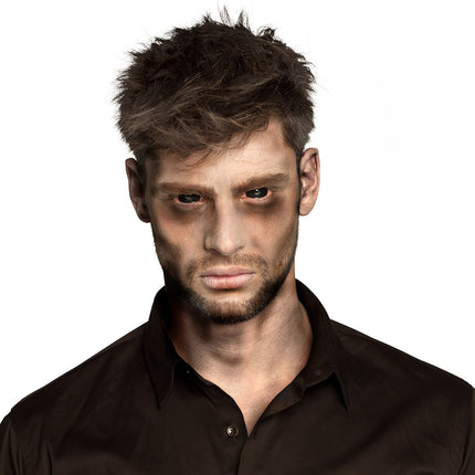 Zombiepoeder aangebracht: donkere oogkassen en grauwe wangen voor een zombielook op een griezelfeest