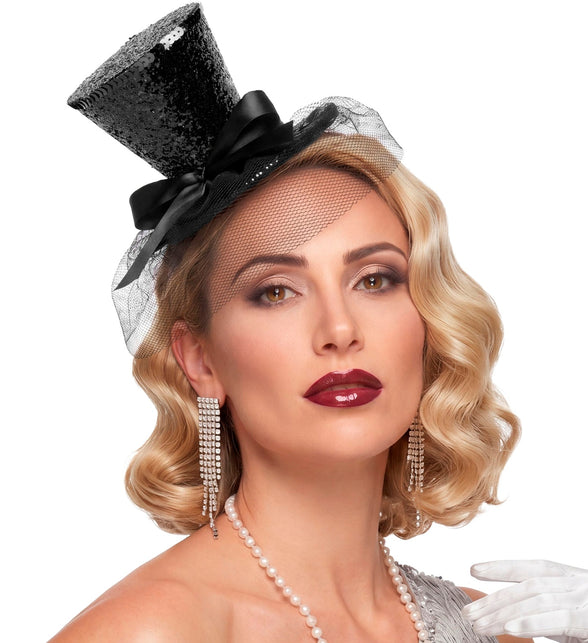 Zwart mini hoedje met sluier bij een klassieke avondlook met glitteroorbellen