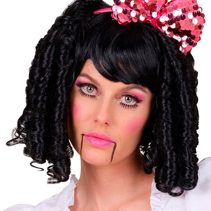 Zwarte pruik speelgoed pop gedragen met een roze strik bij een poppenlook