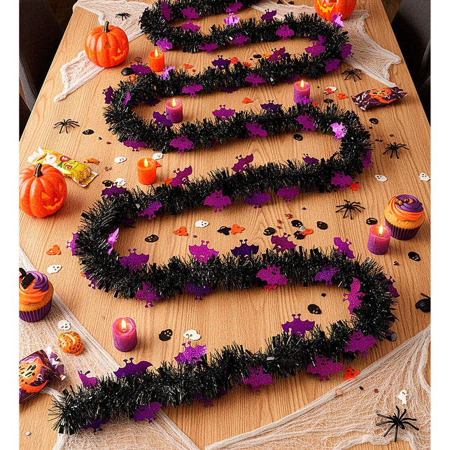 Zwarte vleermuizenslinger in golven over een houten tafel met pompoenen en kaarsen voor Halloween